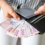 Leather wallet with money in the hands of a woman. Close-up of a woman taking a Turkish lira with a